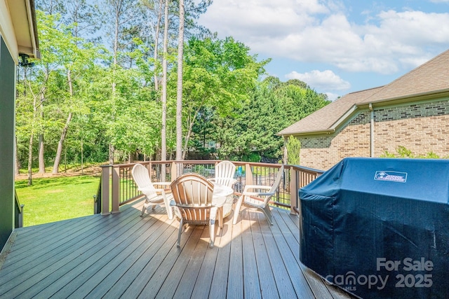 wooden deck with a yard and a grill