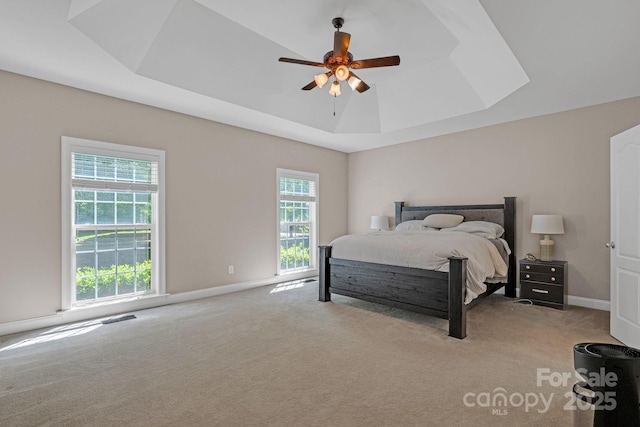 bedroom with visible vents, baseboards, ceiling fan, a raised ceiling, and carpet flooring