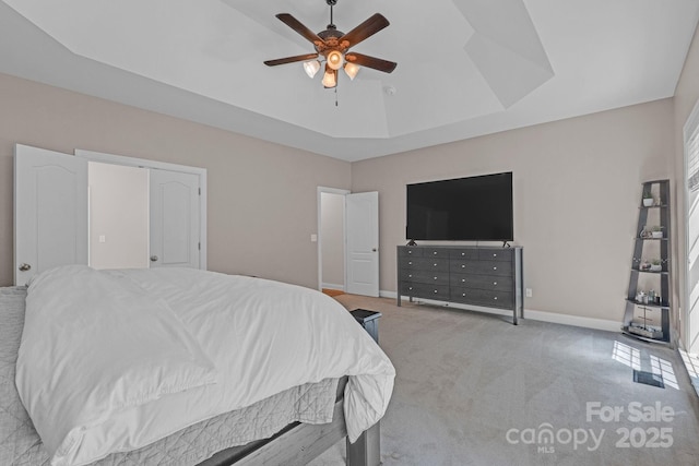 carpeted bedroom featuring baseboards, a ceiling fan, and a raised ceiling