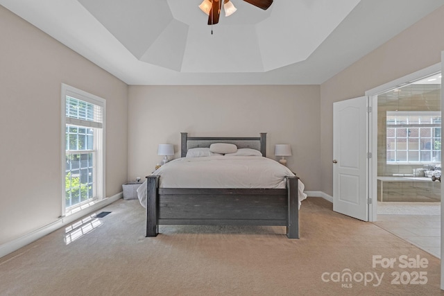 bedroom with ceiling fan, ensuite bath, carpet floors, a tray ceiling, and visible vents