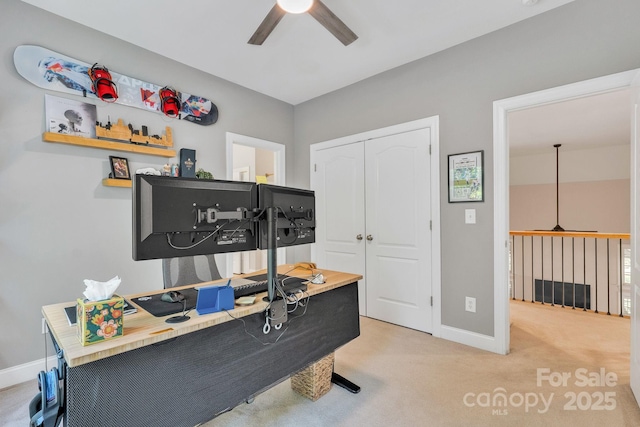 carpeted home office featuring baseboards and ceiling fan