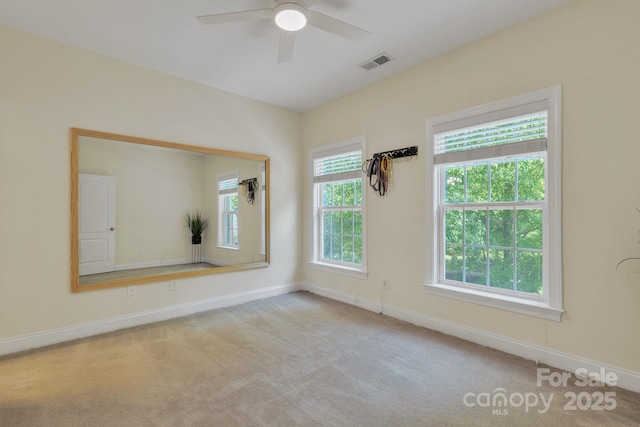 empty room with baseboards, a ceiling fan, carpet floors, and visible vents