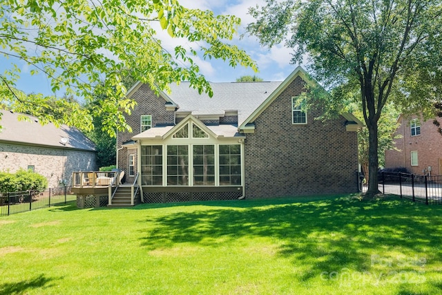 back of house with a lawn, fence, a wooden deck, and a sunroom
