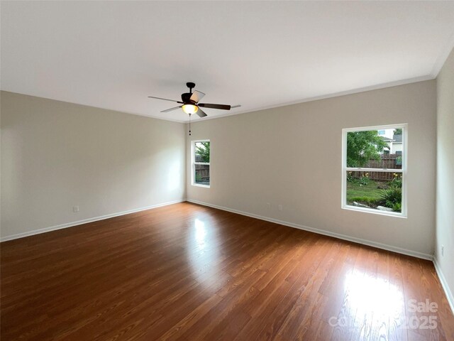 spare room featuring baseboards, ceiling fan, and dark wood-style floors