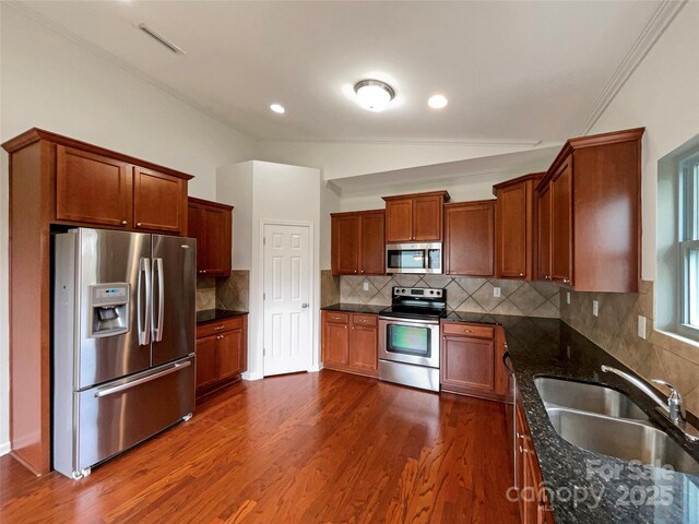 kitchen with a sink, appliances with stainless steel finishes, tasteful backsplash, and dark wood-style flooring