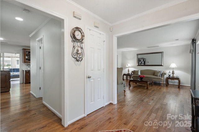 hall featuring crown molding, recessed lighting, baseboards, and wood finished floors