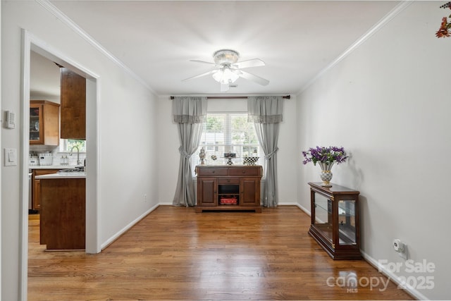 interior space with baseboards, ornamental molding, light wood finished floors, and ceiling fan