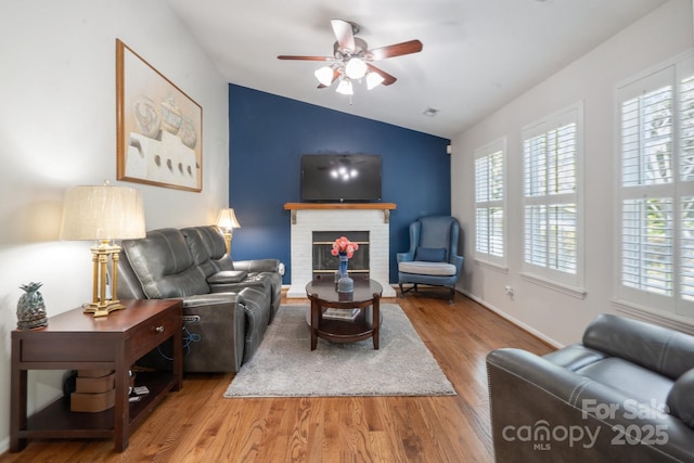 living room featuring a brick fireplace, a ceiling fan, baseboards, wood finished floors, and lofted ceiling