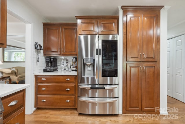 kitchen featuring stainless steel fridge, decorative backsplash, ornamental molding, and brown cabinets