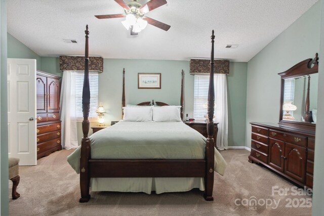 bedroom featuring light colored carpet, a textured ceiling, and visible vents