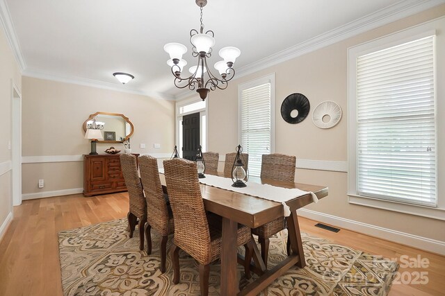 dining space featuring visible vents, crown molding, baseboards, a chandelier, and light wood-style flooring