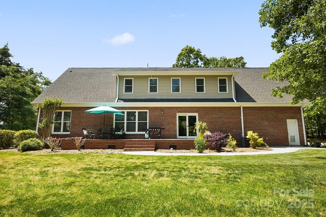 view of front of property with central air condition unit, a shingled roof, a front lawn, and brick siding