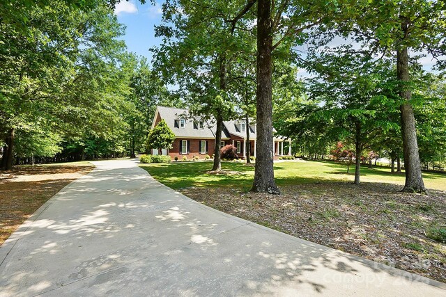 cape cod home with brick siding, a front yard, and concrete driveway