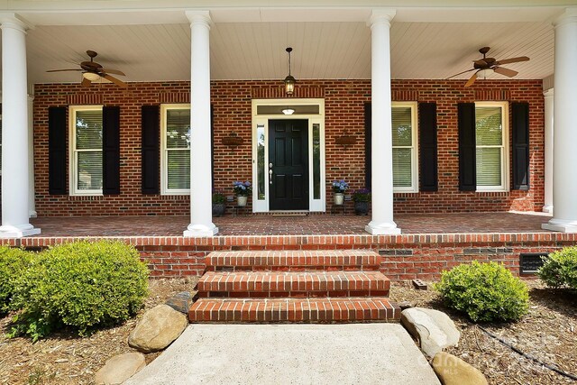 doorway to property featuring a porch, ceiling fan, and brick siding