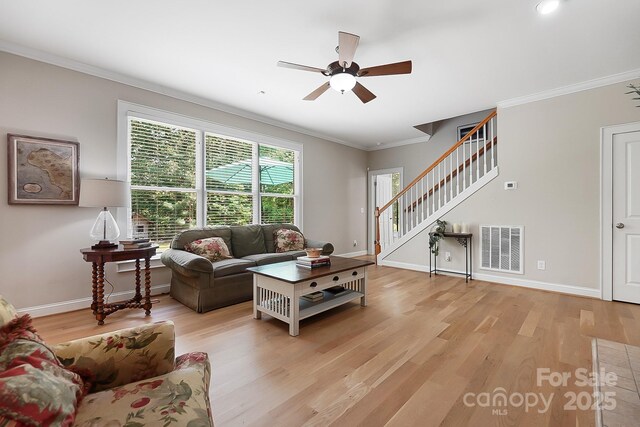 living area featuring ceiling fan, visible vents, stairway, baseboards, and light wood-style flooring