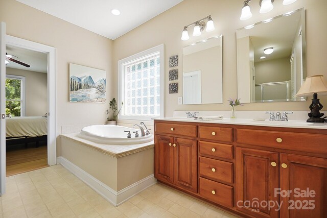 ensuite bathroom with double vanity, a shower with door, ceiling fan, a bath, and a sink