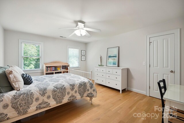 bedroom with baseboards, ceiling fan, visible vents, and light wood-style flooring