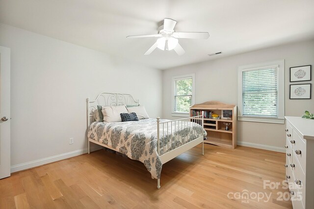 bedroom with baseboards, a ceiling fan, light wood finished floors, and visible vents