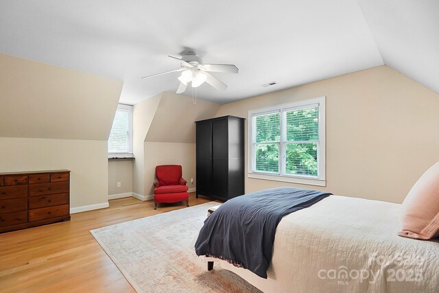 bedroom featuring multiple windows, vaulted ceiling, light wood-style flooring, and visible vents