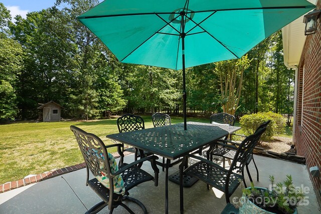 view of patio / terrace with outdoor dining area, an outbuilding, and a storage unit