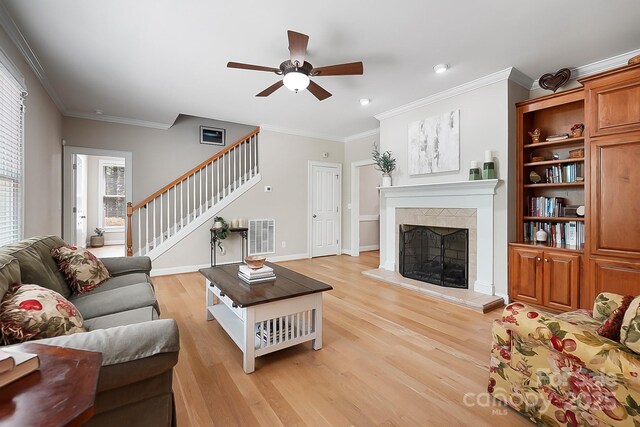 living room with light wood-style floors, plenty of natural light, a ceiling fan, ornamental molding, and stairway