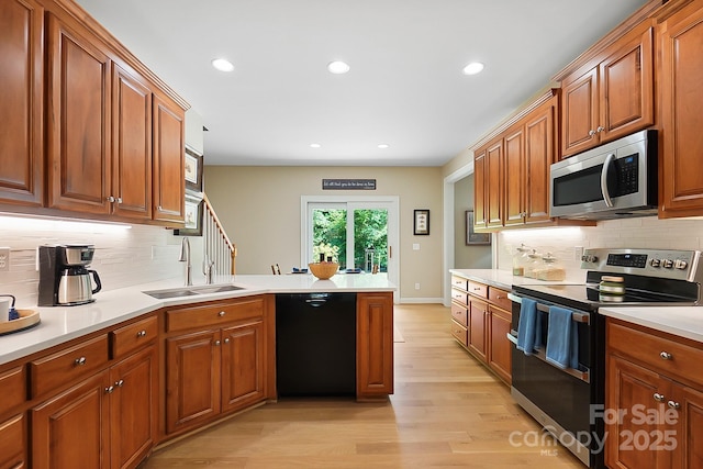 4570 Chanel Ct, Concord, NC 28025 - kitchen featuring appliances with stainless steel finishes, a peninsula, light wood finished floors, tasteful backsplash, and brown cabinets