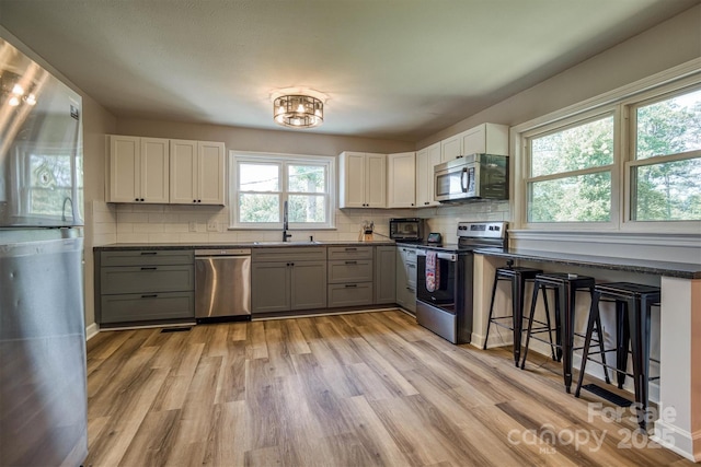 111 Baxter St, Morganton, NC 28655 - kitchen with backsplash, appliances with stainless steel finishes, dark countertops, a sink, and light wood-style flooring