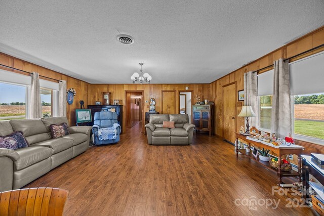 living room with an inviting chandelier, plenty of natural light, wood finished floors, and visible vents