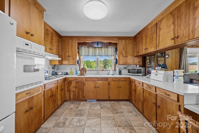 kitchen featuring light countertops, plenty of natural light, white appliances, and a textured ceiling