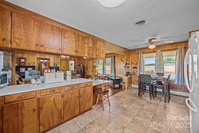 kitchen with brown cabinets, visible vents, freestanding refrigerator, and light countertops