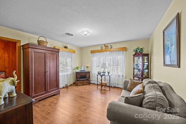 living area featuring a textured ceiling, visible vents, and light wood-type flooring