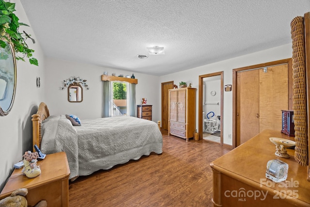 bedroom featuring a textured ceiling, visible vents, and wood finished floors