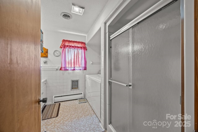 full bathroom featuring visible vents, tile walls, a shower stall, a baseboard radiator, and washer and clothes dryer