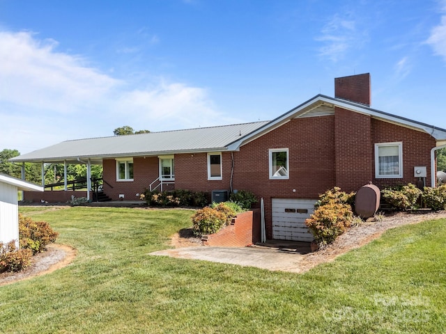 rear view of property with driveway, a chimney, a garage, brick siding, and central AC