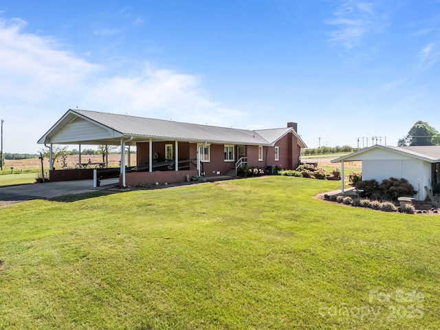 view of front of home with a chimney, an attached carport, driveway, and a front lawn