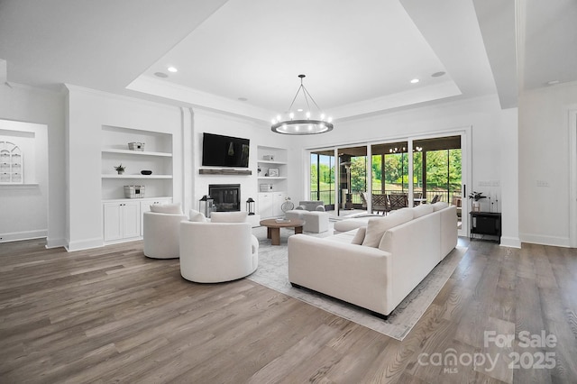 1005 Grand Oak Dr, Waxhaw, NC 28173 - living area with a tray ceiling, built in shelves, a glass covered fireplace, crown molding, and baseboards