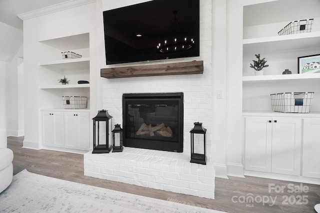 1005 Grand Oak Dr, Waxhaw, NC 28173 - living room featuring wood finished floors, built in shelves, a brick fireplace, and baseboards