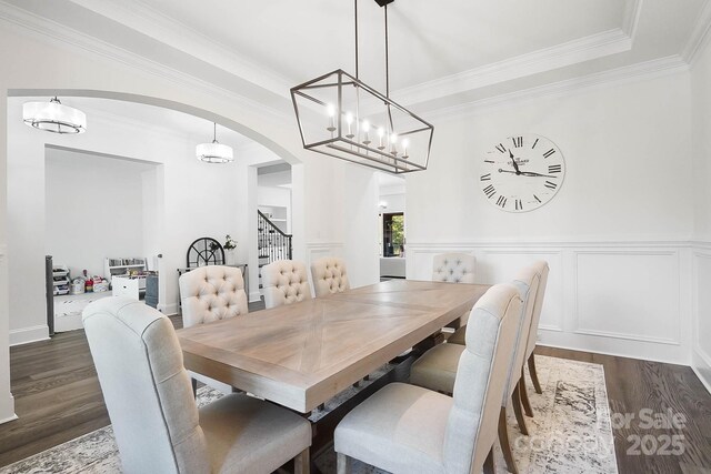 1005 Grand Oak Dr, Waxhaw, NC 28173 - dining area with arched walkways, dark wood-style flooring, stairway, crown molding, and a chandelier