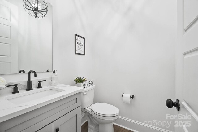 1005 Grand Oak Dr, Waxhaw, NC 28173 - half bath with vanity, toilet, baseboards, and wood finished floors