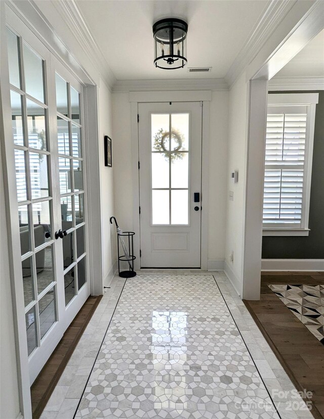doorway with crown molding, baseboards, french doors, and visible vents