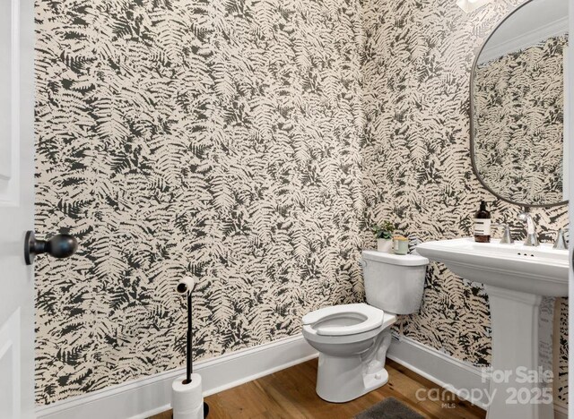 bathroom featuring baseboards, toilet, wallpapered walls, and wood finished floors
