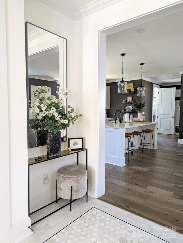 corridor with crown molding, wood finished floors, and a sink
