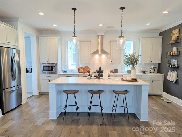 kitchen featuring a breakfast bar, backsplash, wall chimney range hood, and stainless steel appliances