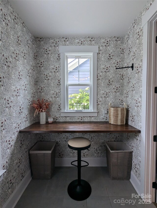 unfurnished office featuring baseboards and tile patterned flooring