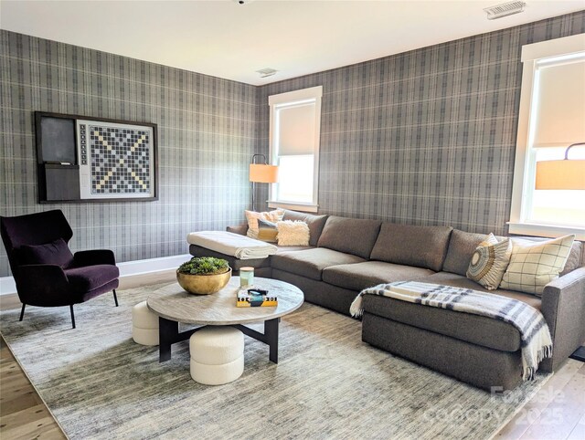 living area featuring wallpapered walls, visible vents, and wood finished floors