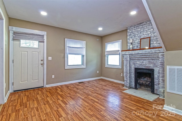 interior space featuring visible vents, a fireplace, wood finished floors, baseboards, and recessed lighting