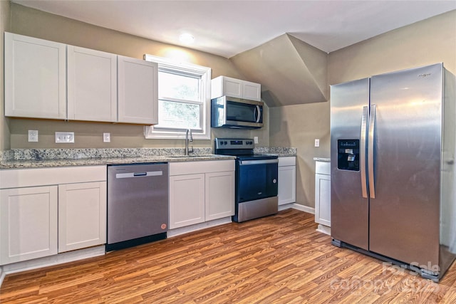 kitchen featuring a sink, appliances with stainless steel finishes, light wood finished floors, and white cabinetry