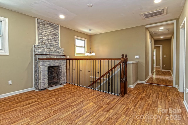 unfurnished living room featuring a fireplace, recessed lighting, baseboards, wood finished floors, and visible vents