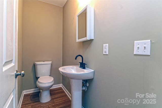 bathroom with baseboards, wood finished floors, and toilet