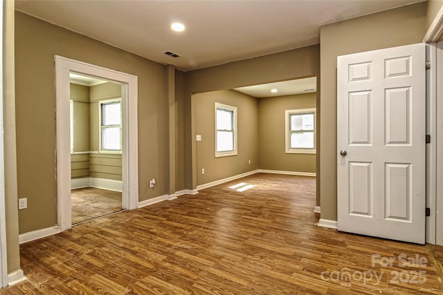 unfurnished room featuring baseboards, a wealth of natural light, wood finished floors, and visible vents